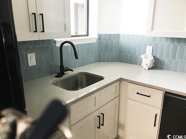 kitchen with a sink, light countertops, dishwasher, and white cabinetry