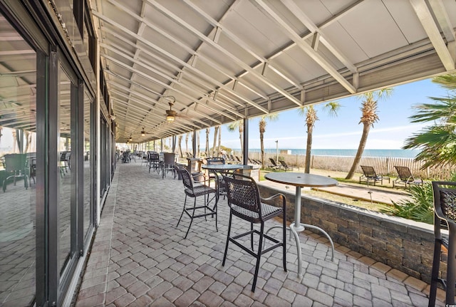 view of patio featuring view of water and beach and fence
