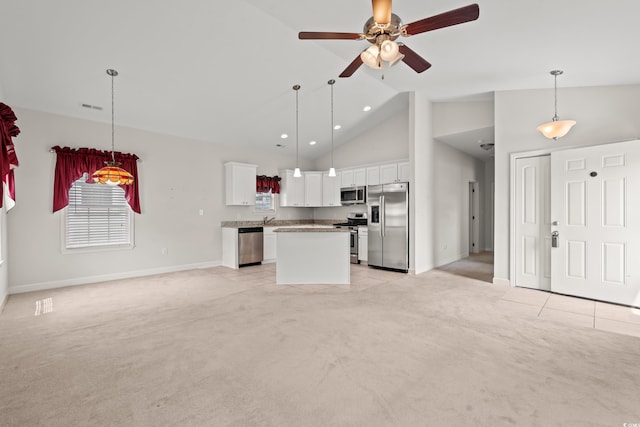 kitchen with a center island, stainless steel appliances, pendant lighting, and light colored carpet