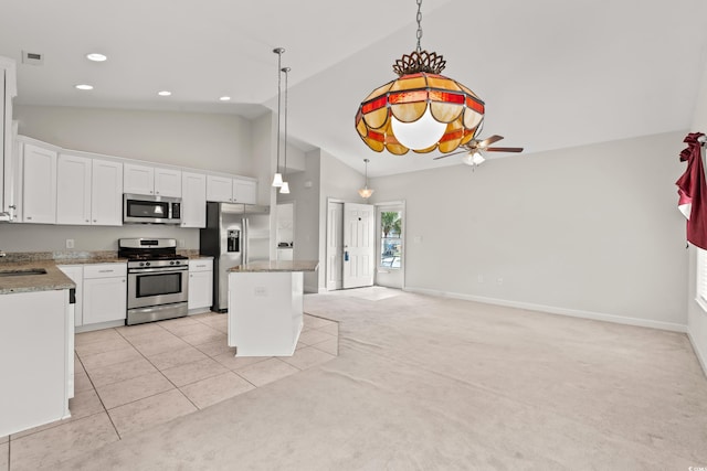 kitchen with appliances with stainless steel finishes, light tile patterned flooring, white cabinetry, and a kitchen island