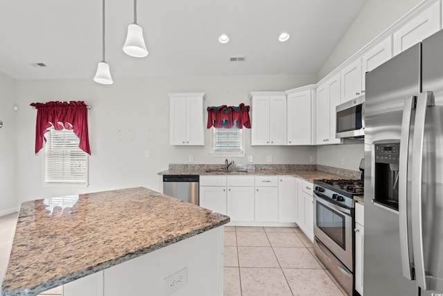 kitchen featuring sink, a center island, light tile patterned floors, stainless steel appliances, and white cabinets