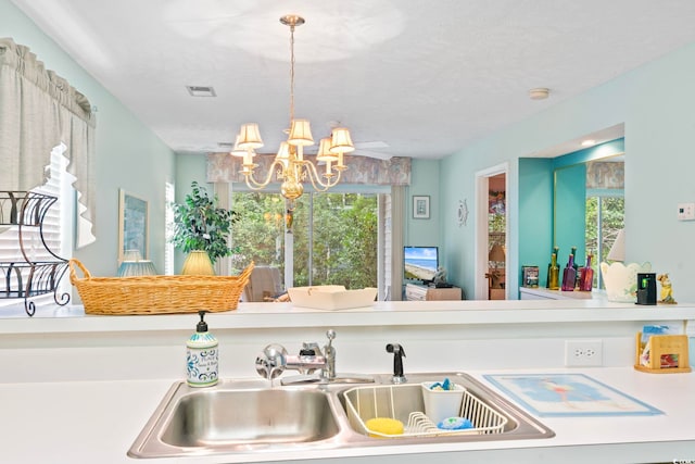 kitchen with sink, a chandelier, and a textured ceiling