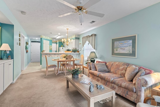 carpeted living room featuring a textured ceiling and ceiling fan with notable chandelier