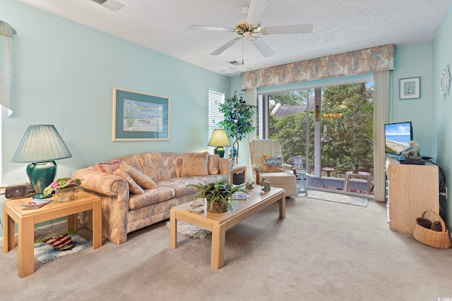 living room with a textured ceiling, ceiling fan, and light carpet