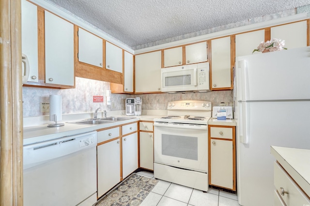 kitchen featuring light countertops, a textured ceiling, a sink, and white appliances