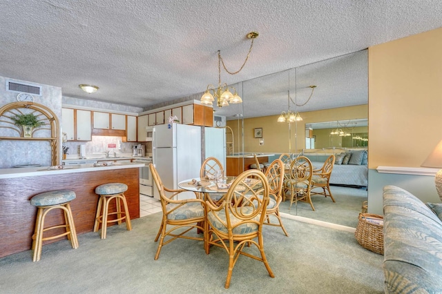 dining area featuring a textured ceiling, a notable chandelier, light carpet, and visible vents