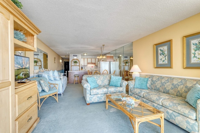 living room featuring a textured ceiling, a notable chandelier, wainscoting, and light carpet