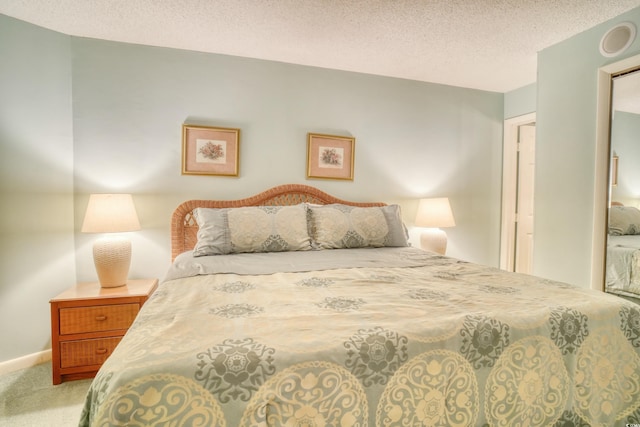 carpeted bedroom with a textured ceiling and baseboards