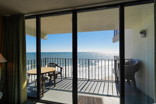 balcony featuring a view of the beach and a water view