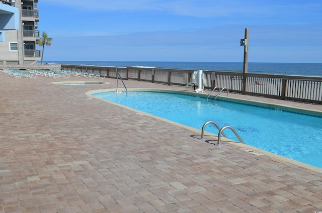 pool with a patio area and a water view