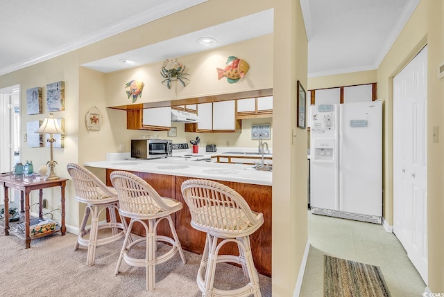 kitchen featuring range, stainless steel microwave, light countertops, crown molding, and white fridge with ice dispenser