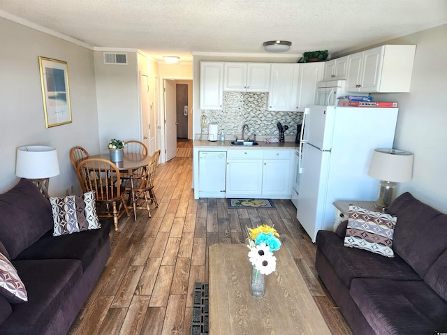 living area with dark wood-type flooring, visible vents, crown molding, and a textured ceiling