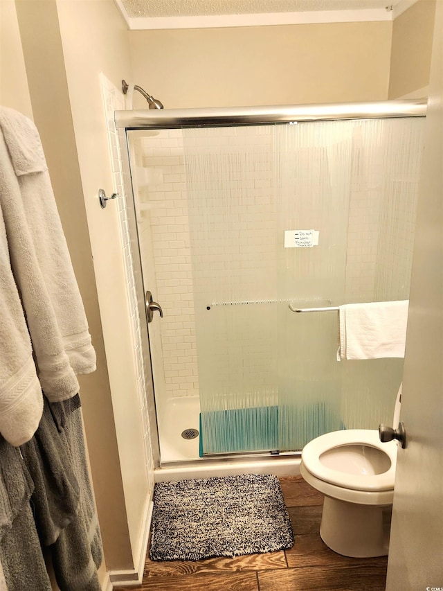 full bath featuring toilet, a shower stall, and wood finished floors