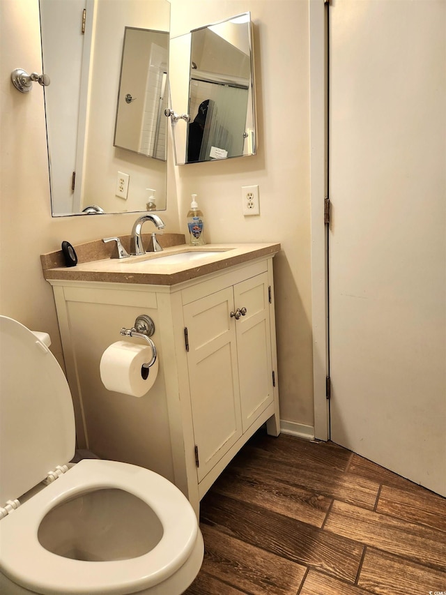 bathroom featuring toilet, wood finished floors, and vanity