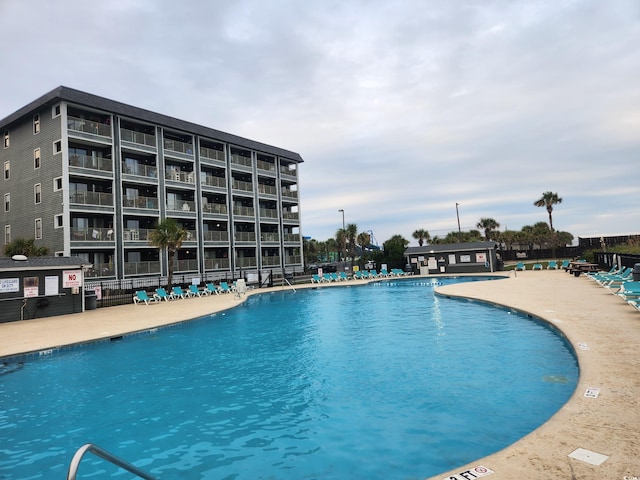 pool with a patio area and fence