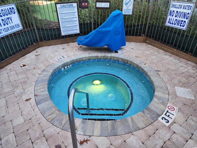 view of swimming pool with fence and a community hot tub