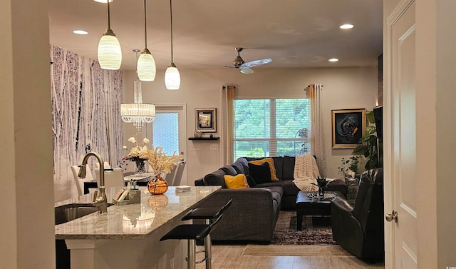 living room with sink, light hardwood / wood-style flooring, and ceiling fan with notable chandelier