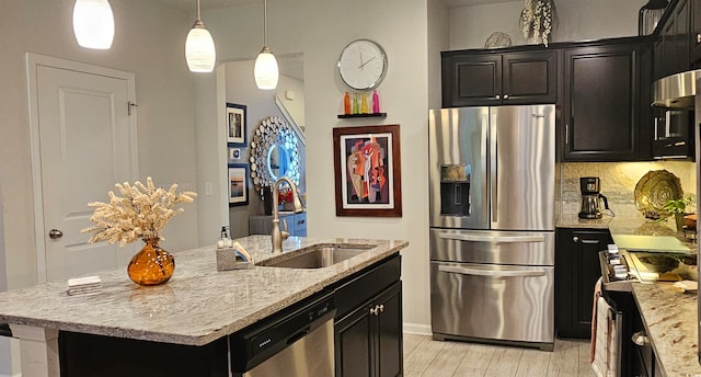 kitchen with decorative backsplash, a kitchen island with sink, light hardwood / wood-style floors, sink, and stainless steel appliances