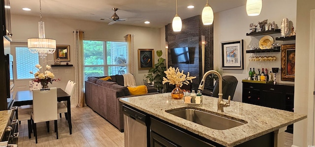 kitchen with dishwasher, light hardwood / wood-style floors, sink, pendant lighting, and ceiling fan with notable chandelier