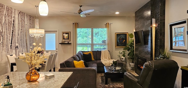 living room with ceiling fan with notable chandelier and a premium fireplace