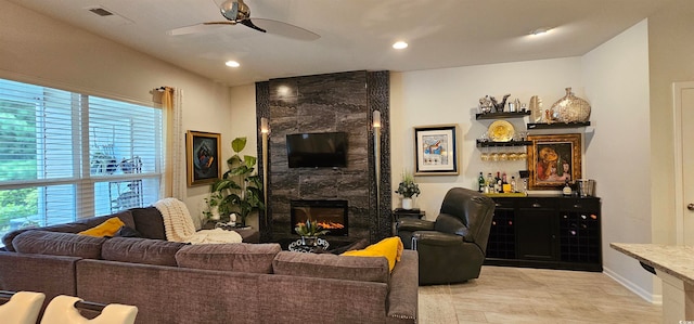 tiled living room featuring ceiling fan and a high end fireplace