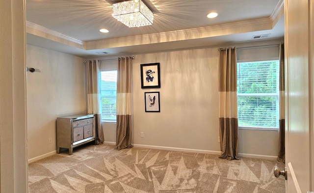 carpeted spare room featuring a wealth of natural light, a raised ceiling, and crown molding