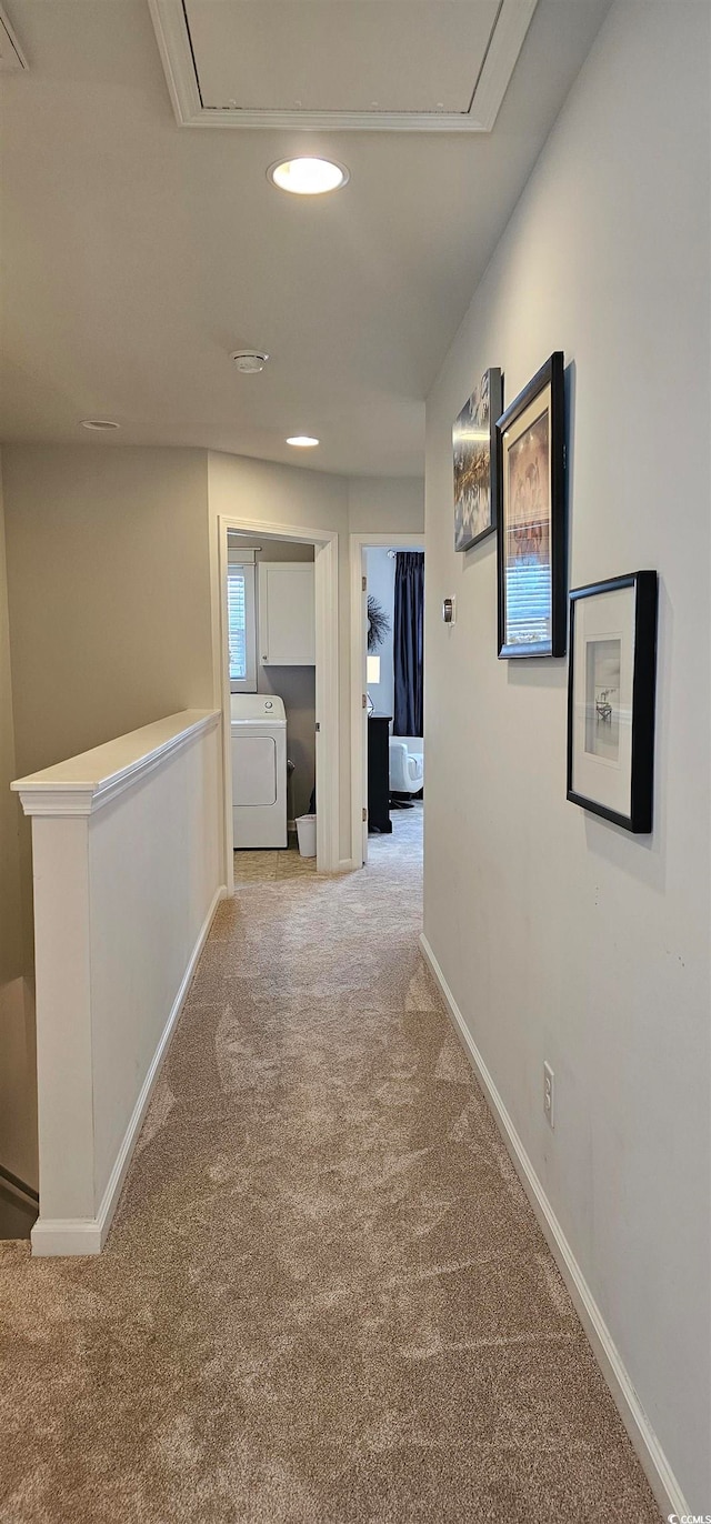 hall with light colored carpet and washer / clothes dryer