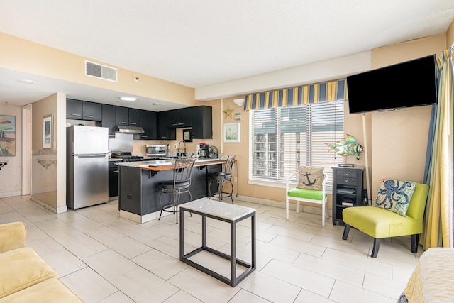 kitchen featuring a breakfast bar, kitchen peninsula, appliances with stainless steel finishes, and light tile patterned flooring