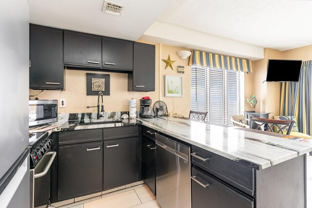 1605 S Ocean Blvd Unit 1104, Myrtle Beach, SC 29577 - kitchen with a peninsula, appliances with stainless steel finishes, a sink, light tile patterned floors, and light stone counters