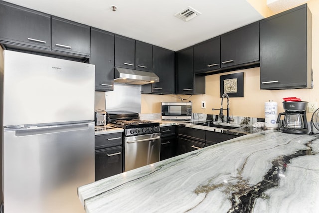 kitchen with appliances with stainless steel finishes, sink, and light stone counters