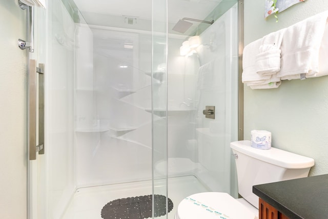 bathroom featuring a shower with door, toilet, and vanity