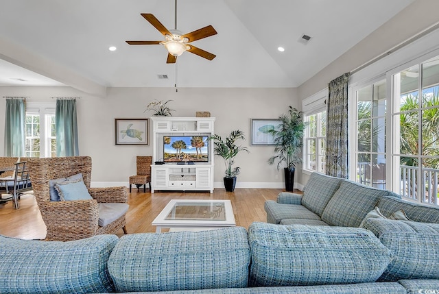 living room with light hardwood / wood-style flooring, vaulted ceiling, ceiling fan, and a wealth of natural light