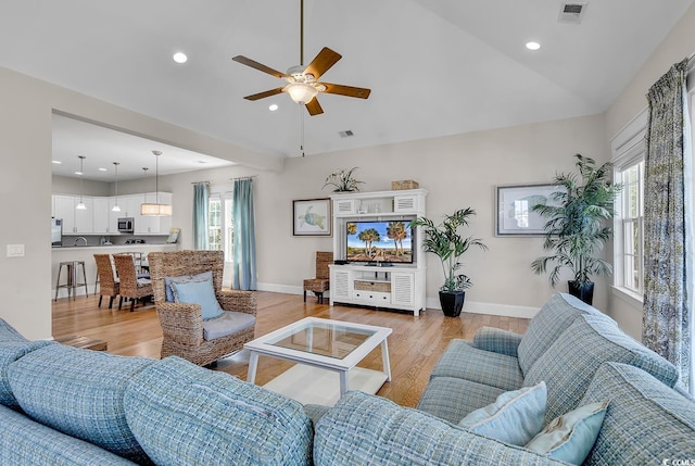 living room featuring light wood-type flooring, vaulted ceiling, and ceiling fan