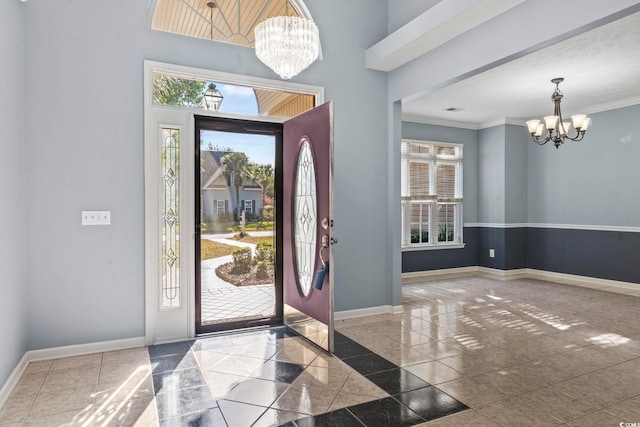 foyer entrance with ornamental molding, a notable chandelier, and a healthy amount of sunlight