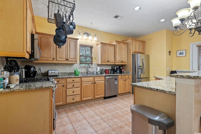 kitchen with light tile patterned floors, light stone countertops, a chandelier, sink, and stainless steel appliances