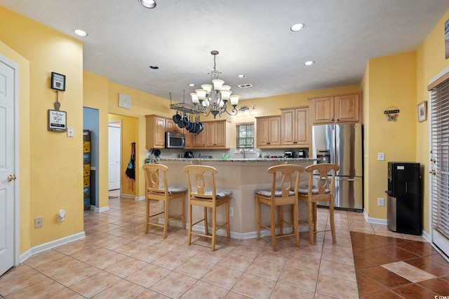 kitchen featuring light tile patterned floors, a kitchen breakfast bar, light stone countertops, a notable chandelier, and stainless steel appliances