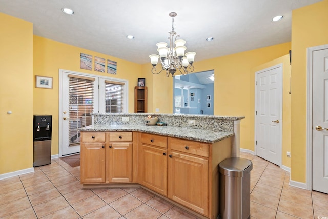 kitchen featuring a kitchen island, light stone countertops, a notable chandelier, pendant lighting, and light tile patterned floors