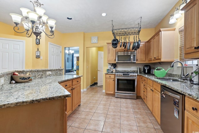 kitchen featuring hanging light fixtures, appliances with stainless steel finishes, light stone countertops, light tile patterned flooring, and sink