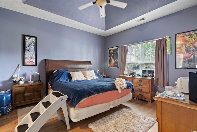 bedroom featuring light hardwood / wood-style flooring, a textured ceiling, and ceiling fan