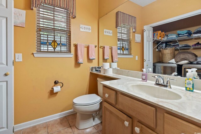 bathroom with a wealth of natural light, vanity, toilet, and tile patterned floors