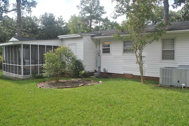 back of property with central air condition unit, a sunroom, and a yard