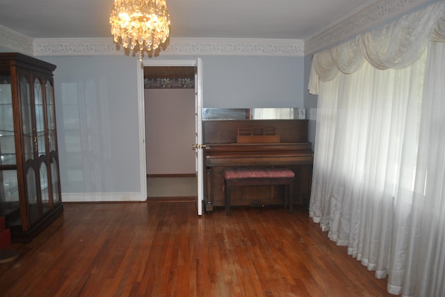 unfurnished living room featuring hardwood / wood-style floors, a wealth of natural light, an inviting chandelier, and ornamental molding