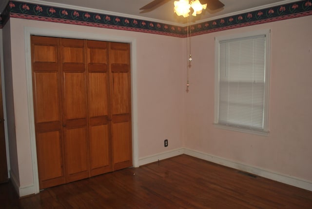 unfurnished bedroom with ceiling fan, crown molding, a closet, and dark hardwood / wood-style flooring