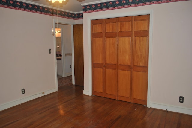 unfurnished bedroom featuring a closet and dark wood-type flooring