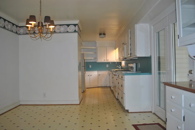 kitchen featuring decorative backsplash, a chandelier, crown molding, stainless steel fridge, and light tile patterned flooring