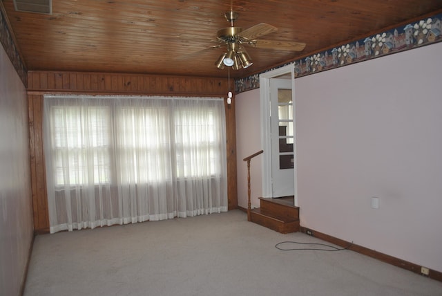 carpeted spare room with ceiling fan, plenty of natural light, and wood ceiling