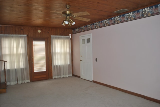 empty room featuring ceiling fan, wooden walls, carpet, and wooden ceiling