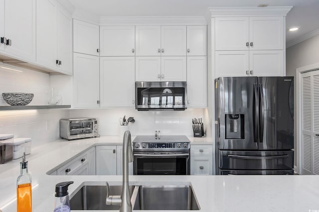 kitchen featuring white cabinets, decorative backsplash, appliances with stainless steel finishes, and ornamental molding