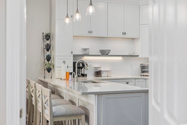 bar featuring white cabinetry, backsplash, sink, and pendant lighting