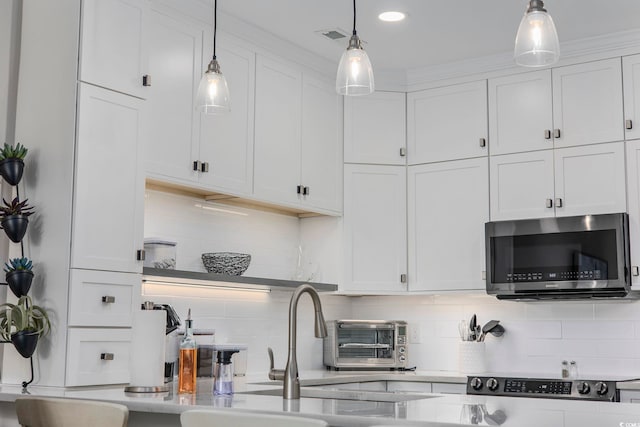 kitchen featuring backsplash, decorative light fixtures, and white cabinets